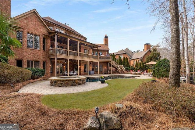 rear view of property with a patio, a chimney, a pool with connected hot tub, a wooden deck, and stairs