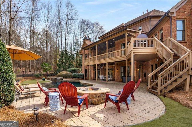 exterior space with a fire pit, an outdoor pool, a sunroom, stairway, and a wooden deck