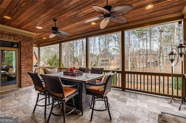 sunroom / solarium featuring wood ceiling and a ceiling fan