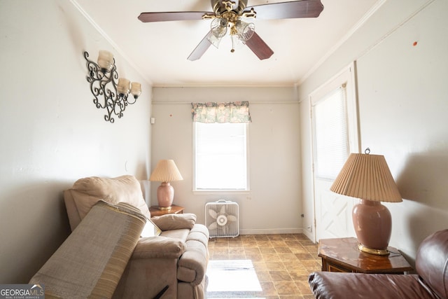 living area featuring crown molding, a ceiling fan, and baseboards