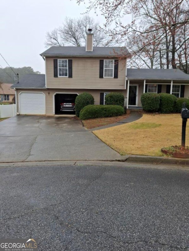 split level home featuring a chimney, aphalt driveway, and a garage