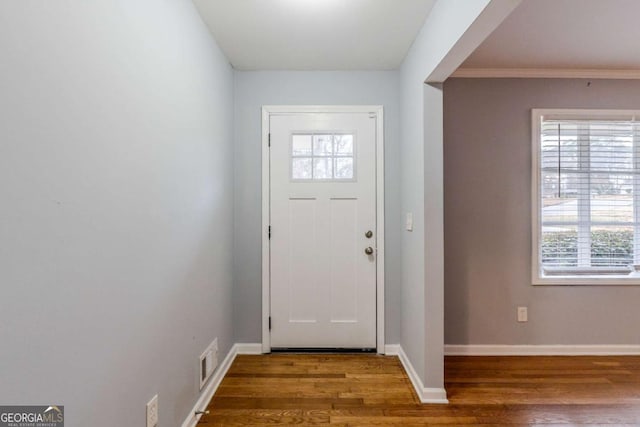 foyer featuring baseboards, wood finished floors, and visible vents