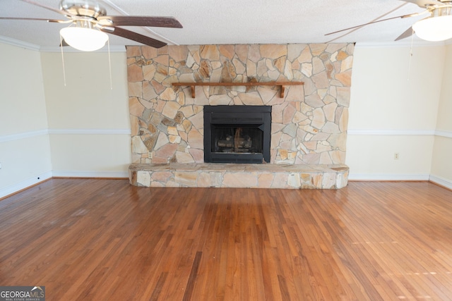 unfurnished living room featuring ceiling fan, crown molding, a textured ceiling, wood finished floors, and a fireplace