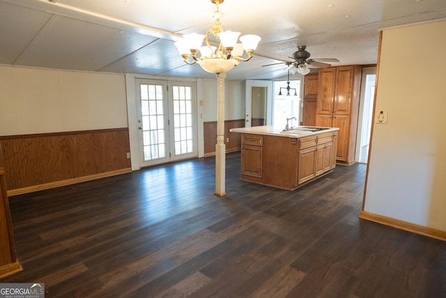 kitchen with light countertops, pendant lighting, dark wood-style flooring, and a center island with sink