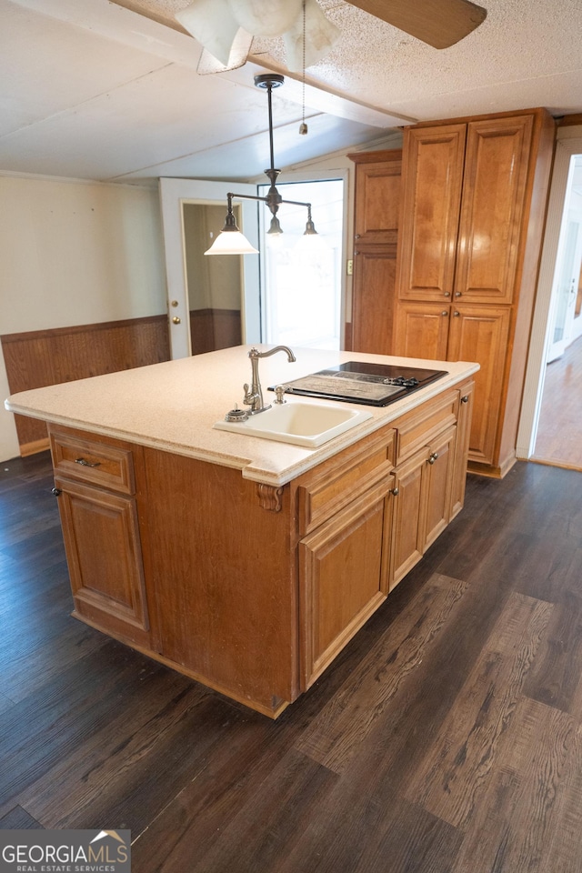 kitchen featuring a kitchen island with sink, decorative light fixtures, light countertops, and a sink