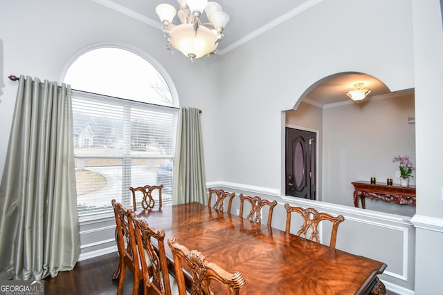 dining space featuring arched walkways, dark wood-type flooring, a notable chandelier, and ornamental molding