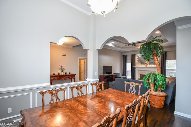 dining area with arched walkways, dark wood finished floors, ornamental molding, a fireplace, and recessed lighting