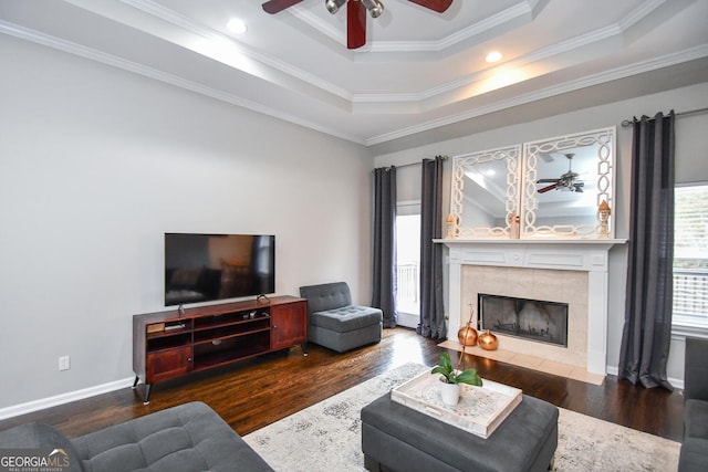 living area with a ceiling fan, a raised ceiling, a fireplace, and dark wood finished floors