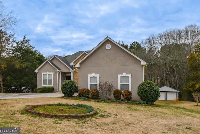 view of front facade featuring a detached garage, a front lawn, an outbuilding, and stucco siding