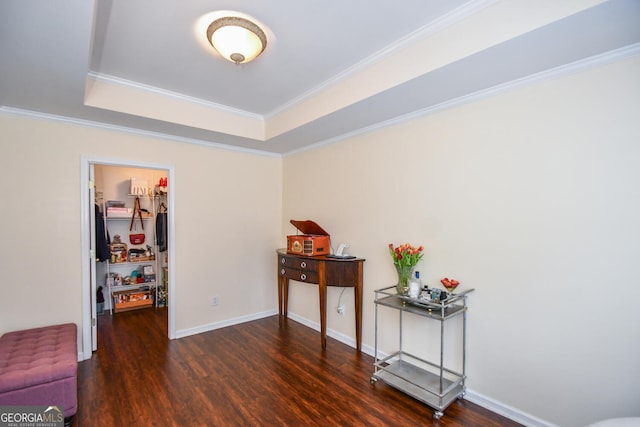 interior space with a raised ceiling, ornamental molding, dark wood finished floors, and baseboards