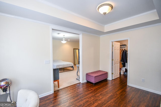 bedroom featuring dark wood-style floors, a raised ceiling, crown molding, and baseboards