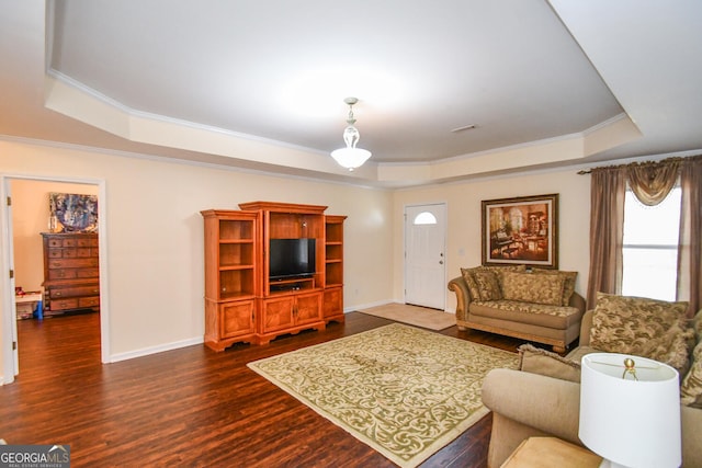 living area featuring dark wood-style flooring, visible vents, baseboards, ornamental molding, and a raised ceiling