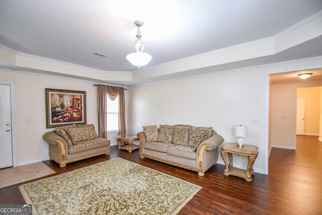 living area featuring a tray ceiling, ornamental molding, dark wood-style flooring, and visible vents