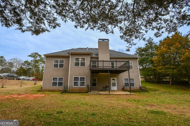 rear view of house featuring a patio, a chimney, stucco siding, a lawn, and a wooden deck