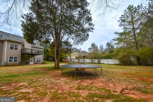 view of yard featuring a trampoline and fence