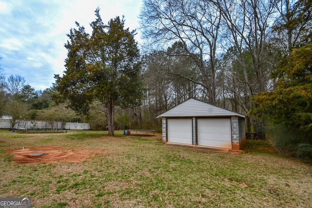 view of yard with a garage, an outbuilding, and fence