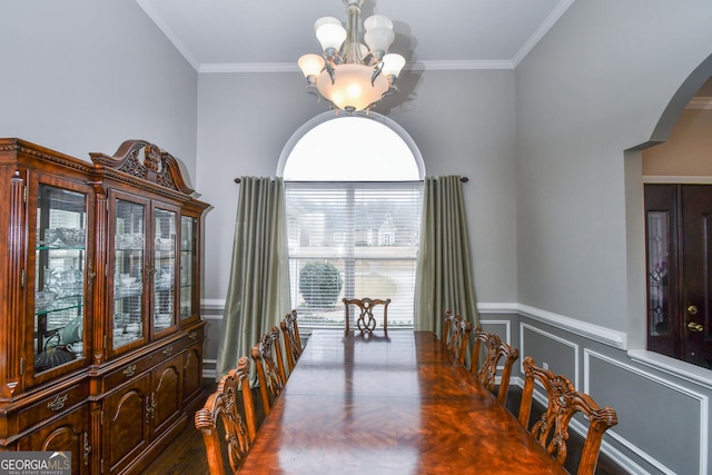 dining area featuring ornamental molding, a chandelier, arched walkways, and a decorative wall