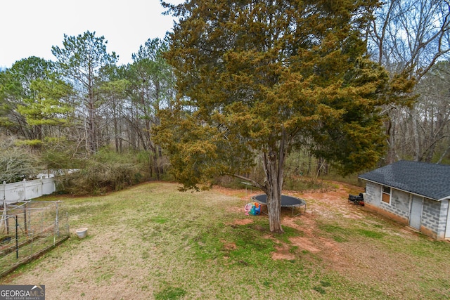 view of yard with a trampoline and fence