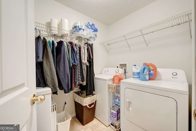 washroom with light floors, laundry area, washer and clothes dryer, and a textured ceiling