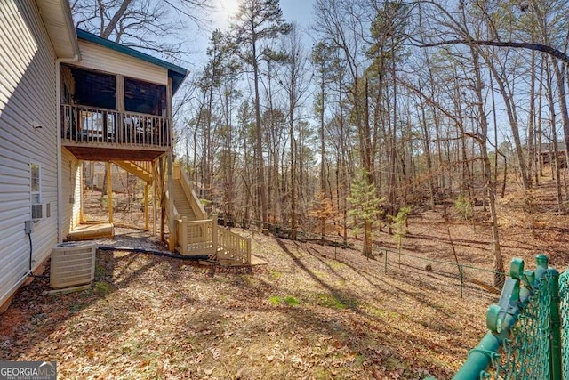 view of yard with central AC, stairway, a sunroom, and cooling unit