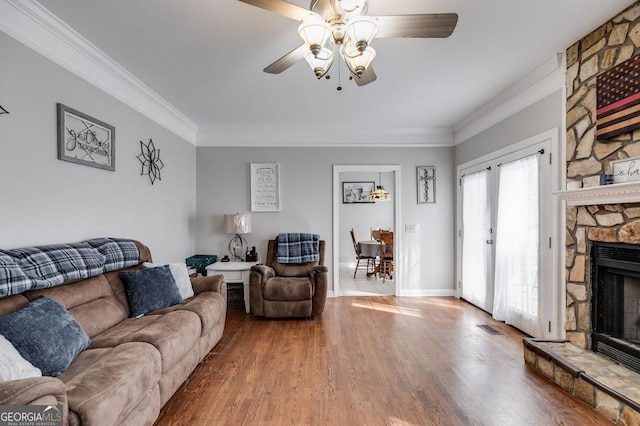 living room with crown molding, a ceiling fan, wood finished floors, and a fireplace