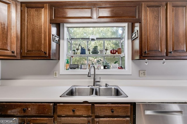 kitchen with light countertops, stainless steel dishwasher, and a sink