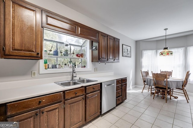 kitchen with a sink, hanging light fixtures, light countertops, light tile patterned flooring, and dishwasher