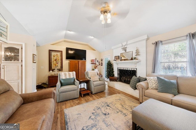 living room featuring a fireplace, lofted ceiling, a ceiling fan, and light wood-style floors