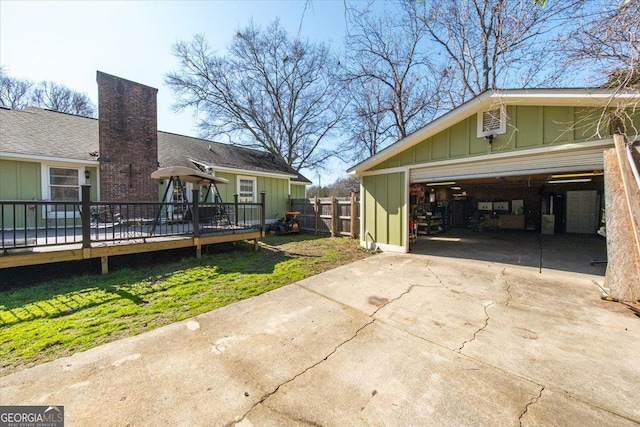 view of side of home featuring fence, a wooden deck, an outbuilding, board and batten siding, and a yard