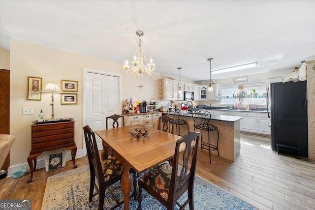 dining space featuring baseboards, an inviting chandelier, and light wood finished floors