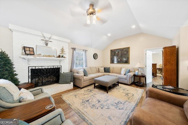 living area featuring a ceiling fan, wood finished floors, a fireplace, and lofted ceiling