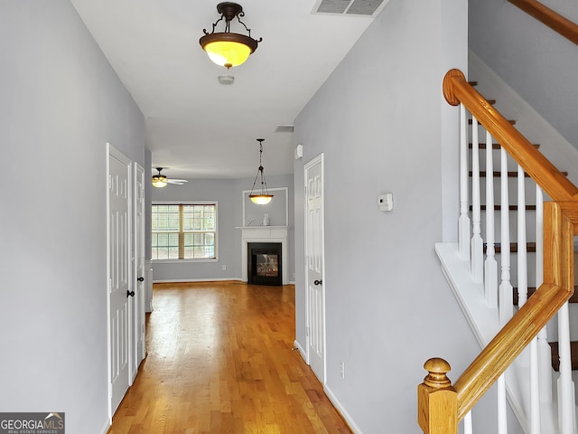 hallway featuring light wood finished floors, baseboards, stairs, and visible vents