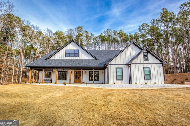 modern inspired farmhouse featuring roof with shingles, a porch, board and batten siding, and a front yard