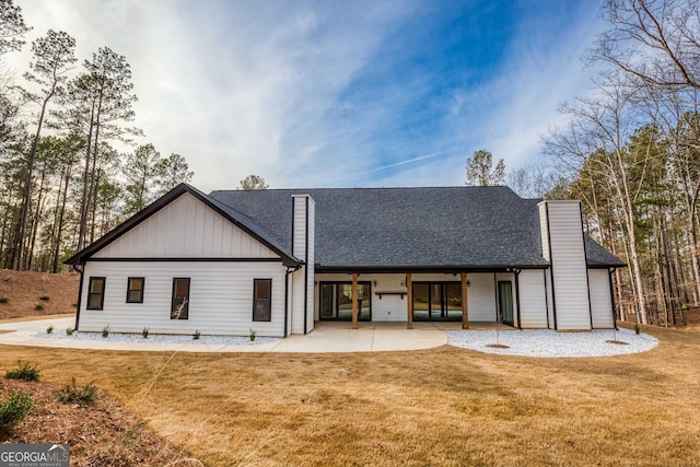 back of property with roof with shingles, a yard, a patio, and a chimney