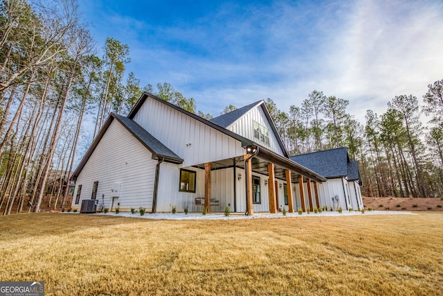 view of front of home with central air condition unit, a front lawn, a shingled roof, and board and batten siding