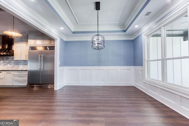 unfurnished dining area featuring visible vents, dark wood finished floors, a raised ceiling, a decorative wall, and a notable chandelier