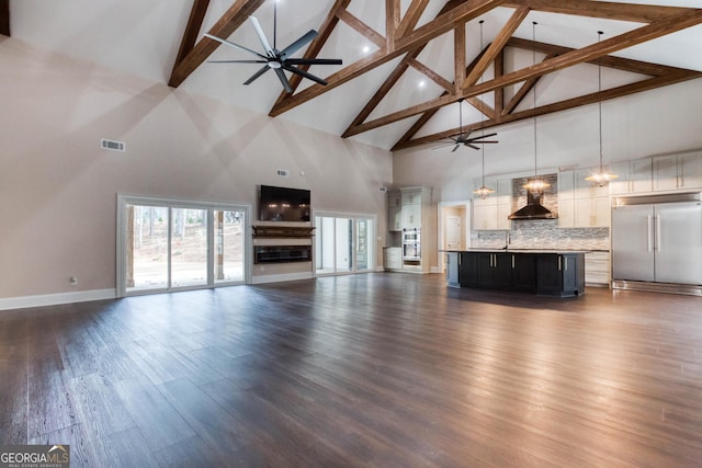 unfurnished living room with ceiling fan, visible vents, dark wood-type flooring, and a sink