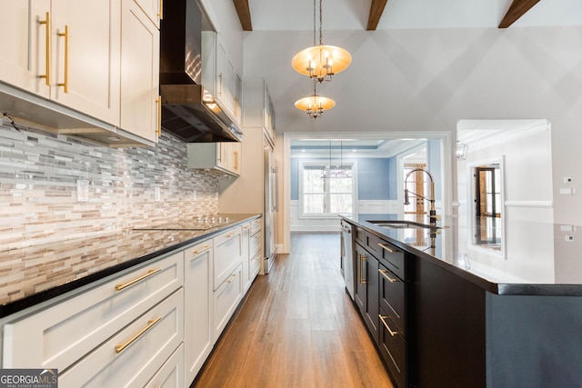 kitchen featuring a sink, dark countertops, pendant lighting, and wall chimney exhaust hood