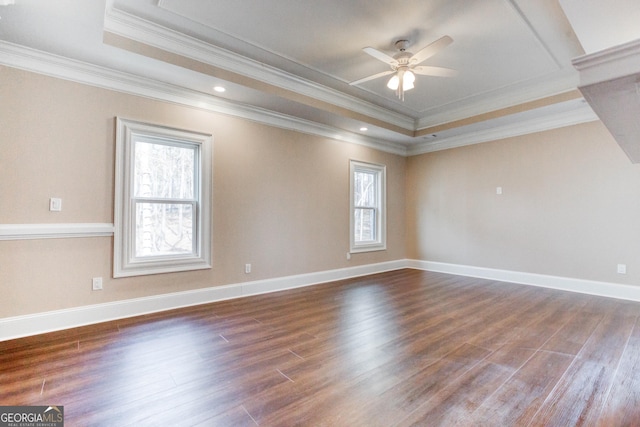 empty room featuring dark wood-style floors, ornamental molding, a raised ceiling, baseboards, and ceiling fan