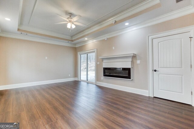 unfurnished living room featuring ceiling fan, baseboards, a raised ceiling, dark wood finished floors, and a glass covered fireplace