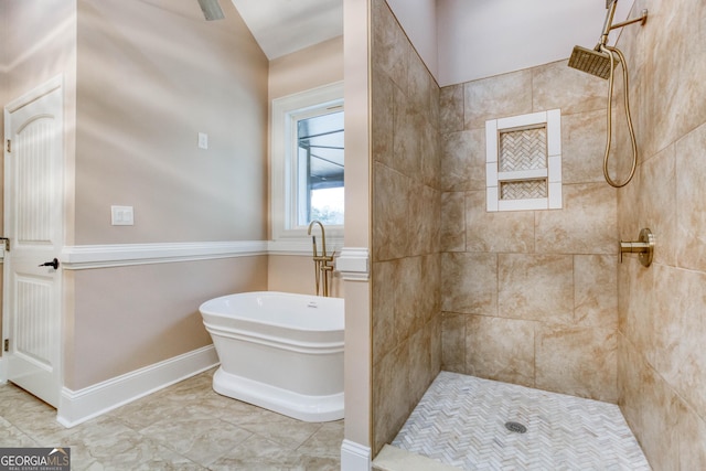 bathroom with a freestanding bath, baseboards, and a tile shower
