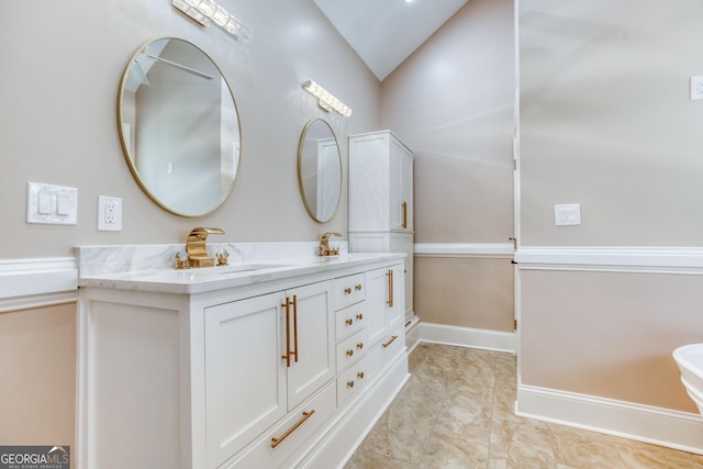 bathroom with double vanity, baseboards, a sink, and lofted ceiling