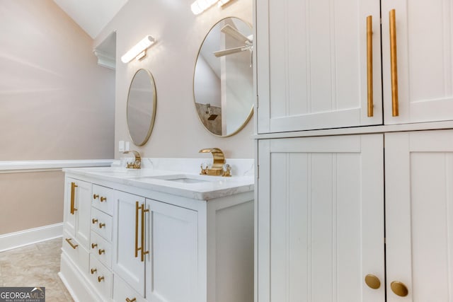 bathroom with double vanity, baseboards, and a sink