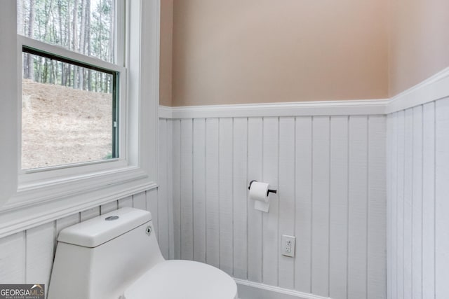 bathroom featuring wainscoting, a healthy amount of sunlight, and toilet