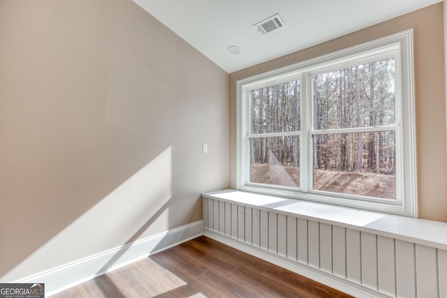 unfurnished room featuring baseboards, vaulted ceiling, visible vents, and wood finished floors