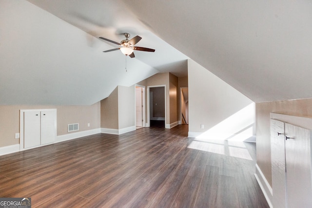 additional living space with ceiling fan, visible vents, baseboards, vaulted ceiling, and dark wood-style flooring