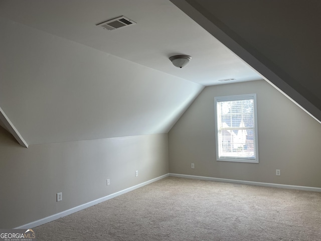 additional living space with baseboards, visible vents, lofted ceiling, and carpet