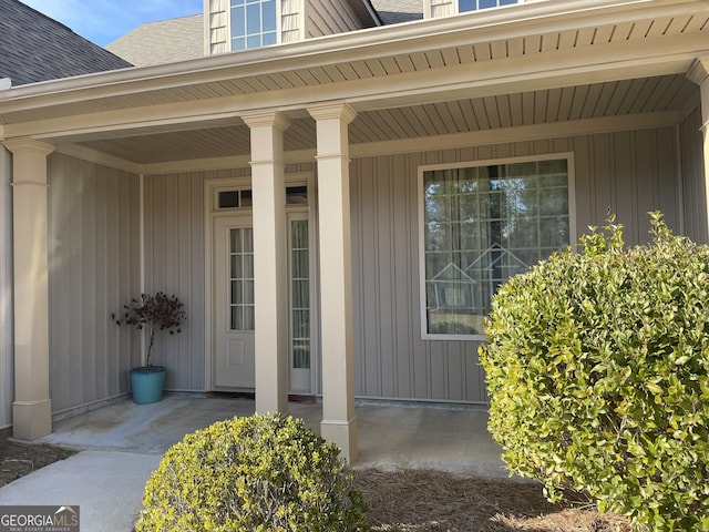 doorway to property featuring roof with shingles and a porch