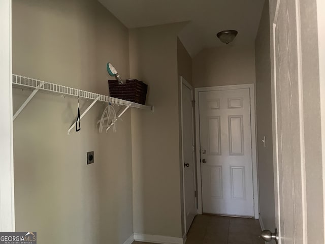 washroom with electric dryer hookup, laundry area, and dark tile patterned flooring