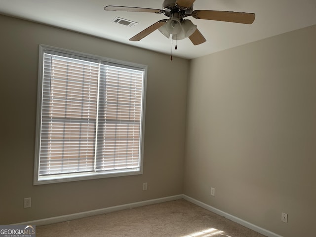 carpeted spare room with baseboards, visible vents, and a ceiling fan